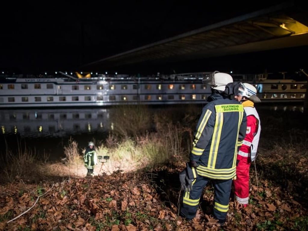 Einsatzkräfte der Feuerwehr am Rhein in Duisburg. Im Fluss liegt das Ausflugsschiff. Foto: Marcel Kusch