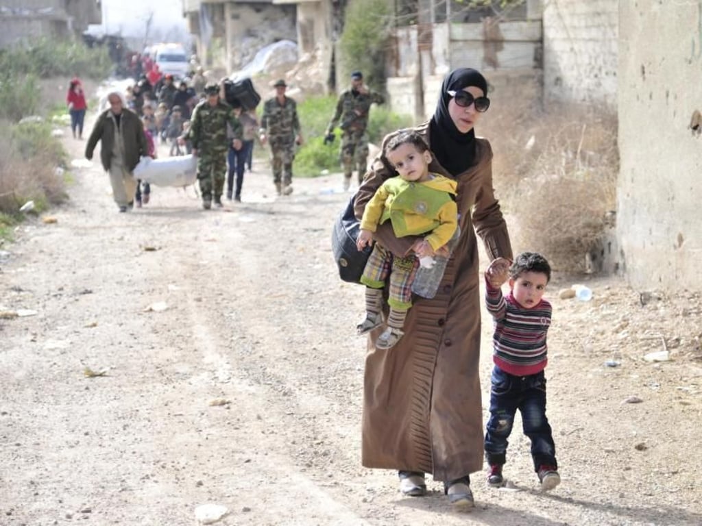 Eine Mutter verlässt mit ihren Kindern das umkämpfte Rebellengebiet. Foto: Sana/AP