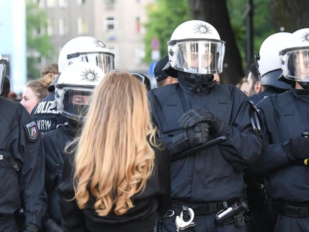 Eine Frau steht auf der revolutionären 1. Mai Demonstration vor Polizisten. In der Vergangenheit war es immer wieder zu Ausschreitungen bei Protestzügen linker und linkextremer Gruppen gekommen. Foto: Ralf Hirschberger