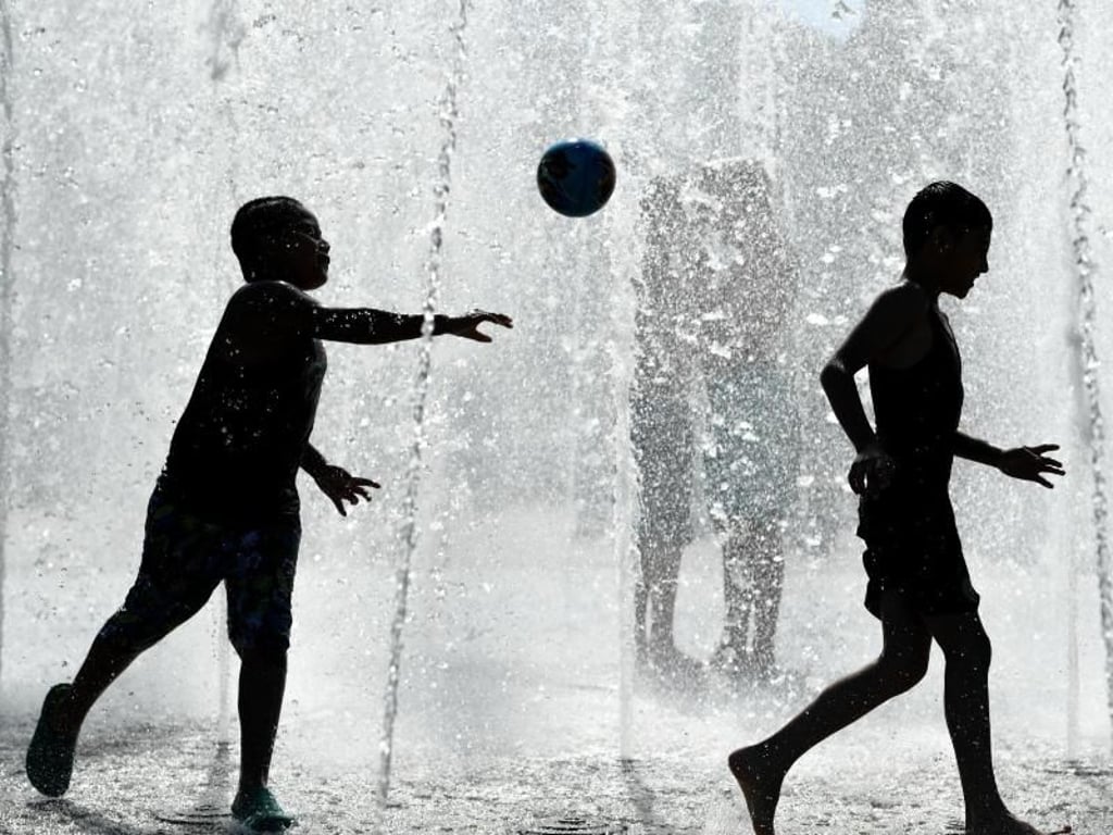 Kinder spielen in Frankfurt am Main bei hochsommerlichen Temperaturen in einem Springbrunnen. Foto: Arne Dedert