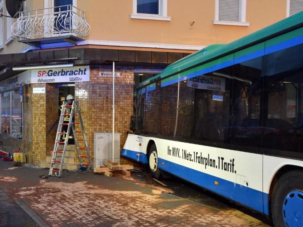 Der beschädigte Schulbus steht nach dem Unfall an der Fassade des Hauses. Foto: Rene Priebe