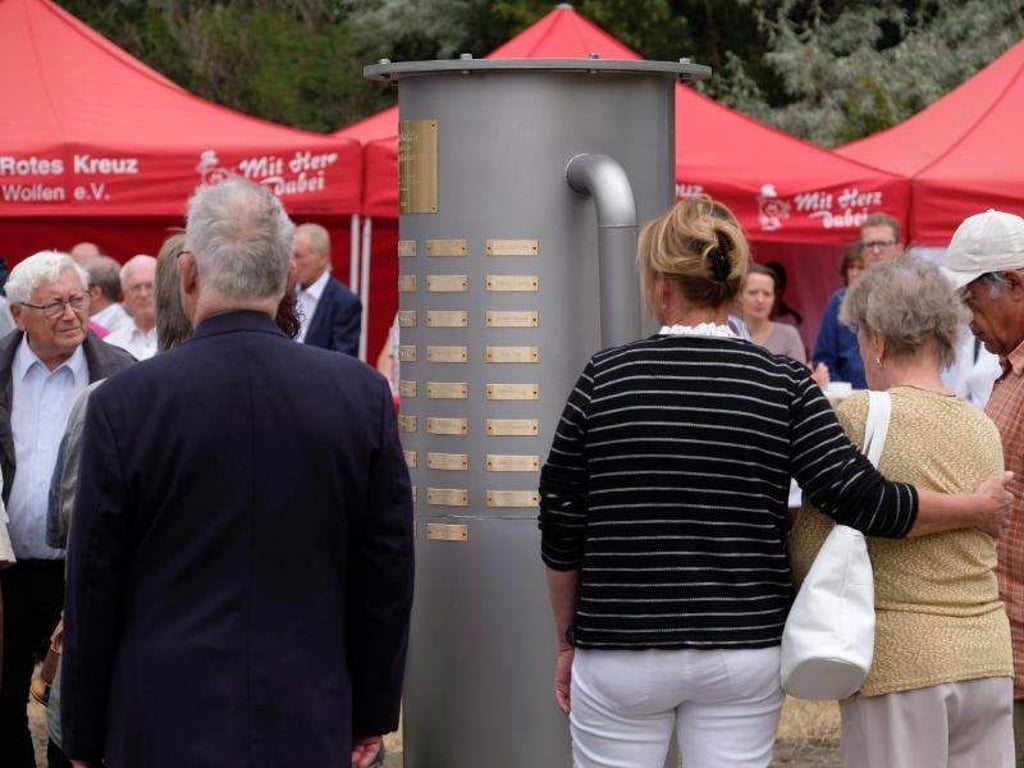 Teilnehmer einer Gedenkveranstaltung stehen am Chemiepark an einem Denkmal. Foto: Sebastian Willnow