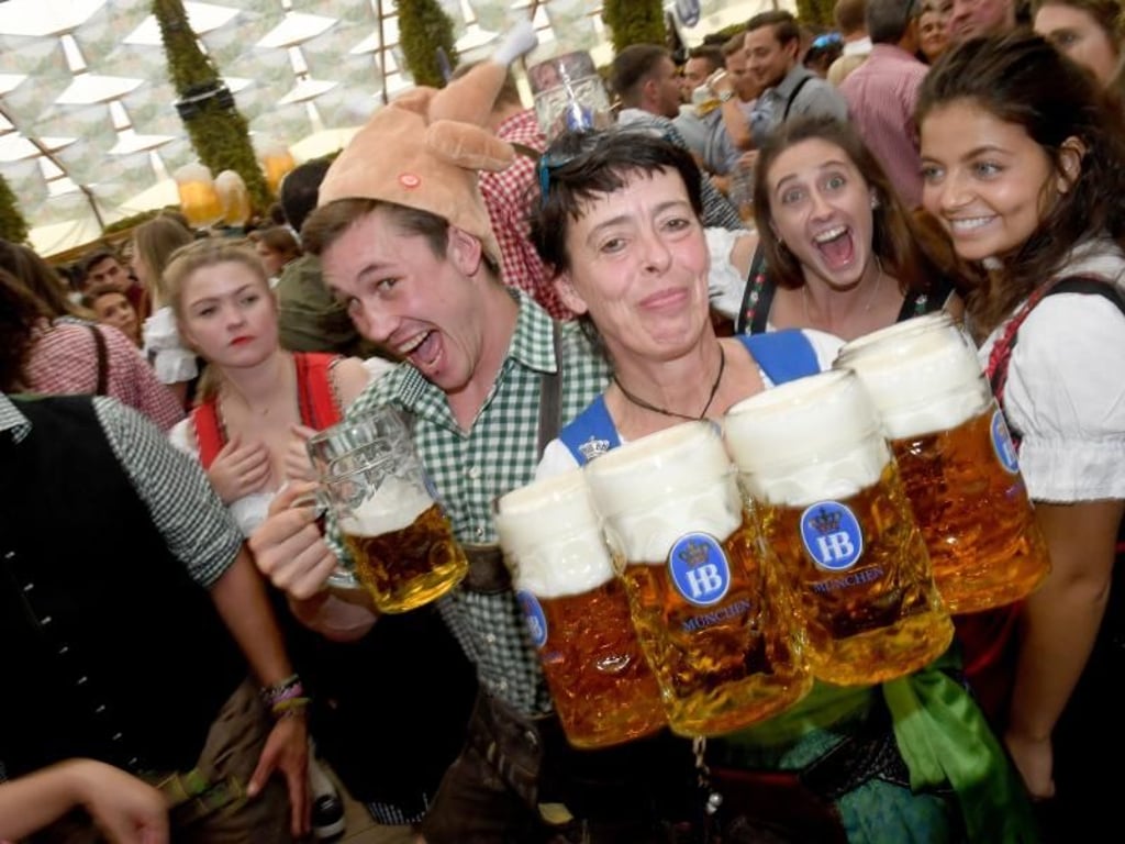Eine Bedienung feiert im Hobräuzeit auf dem Oktoberfest mit einem Gast den Beginn des Oktoberfests. Foto: Felix Hörhager