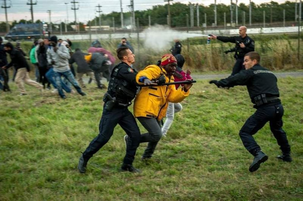 TOPSHOTS
French gendarmes try to stop migrants on the Eurotunnel site in Coquelles near Calais, northern France, on late July 29, 2015. One man died Wednesday in a desperate attempt to reach England via the Channel Tunnel as overwhelmed authorities fought off hundreds of migrants, prompting France to beef up its police presence. AFP PHOTO / PHILIPPE HUGUEN