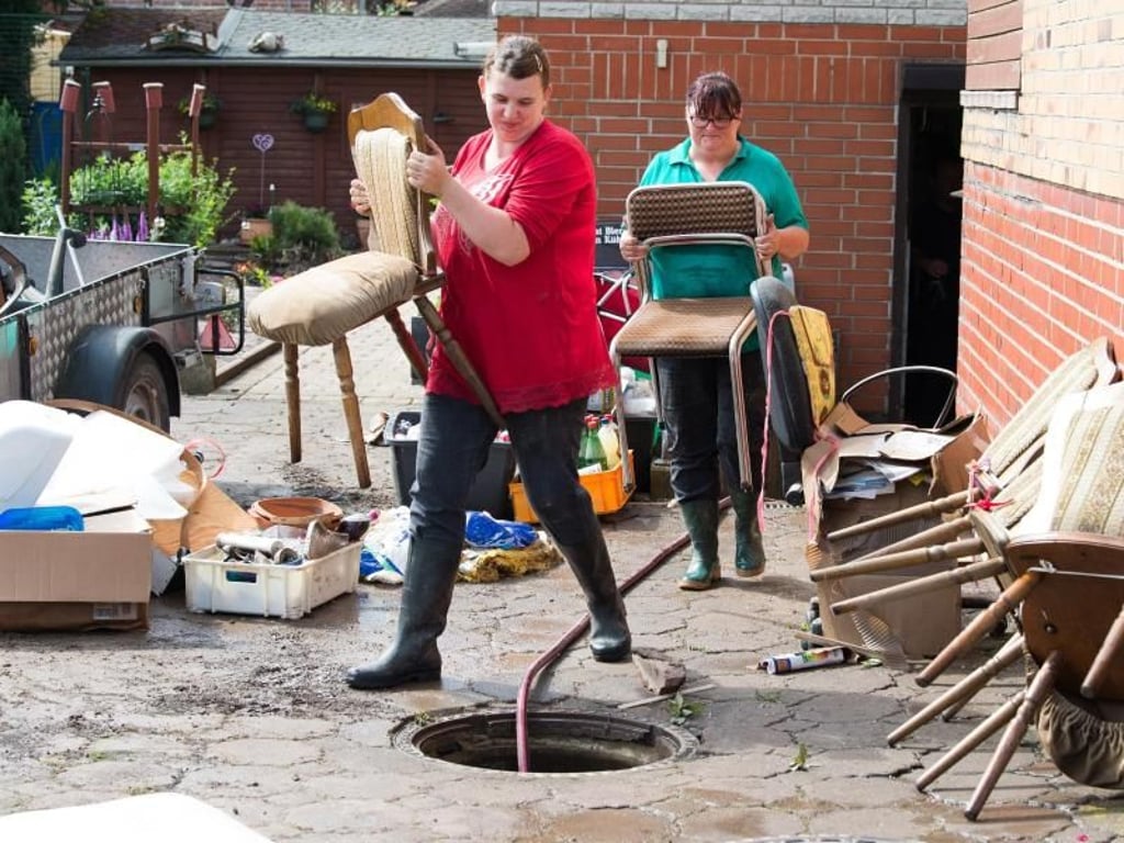 Die beiden Frauen tragen im niedersächsischen Rhüden Möbel aus dem Keller eines Hauses, das vom Hochwasser betroffen ist. Foto: Swen Pförtner