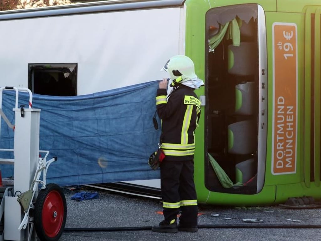 Ein Feuerwehrmann schirmt die Unfallstelle vom verunglückten Bus ab. Foto: Jan Woitas