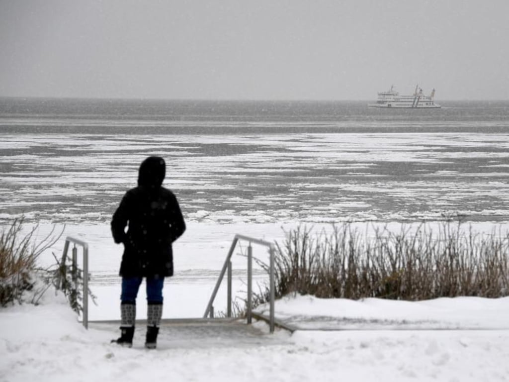 Der Strand von Wyk auf der Insel Föhr liegt unter einer Schneedecke. Im Hintergrund ist eine Fähre von der Insel Amrum zu sehen. Foto: Carsten Rehder