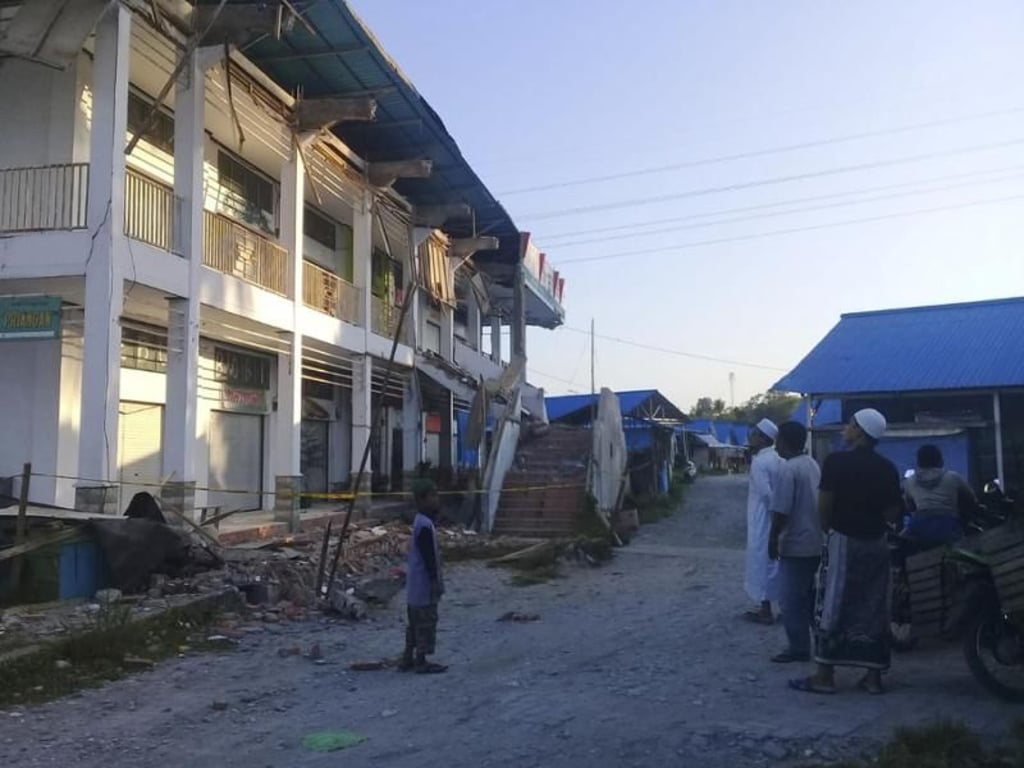 Menschen stehen vor ein durch das Erdbeben beschädigtes Gebäude in Poso, Zentral-Sulawesi. Foto: Yoanes Litha/AP