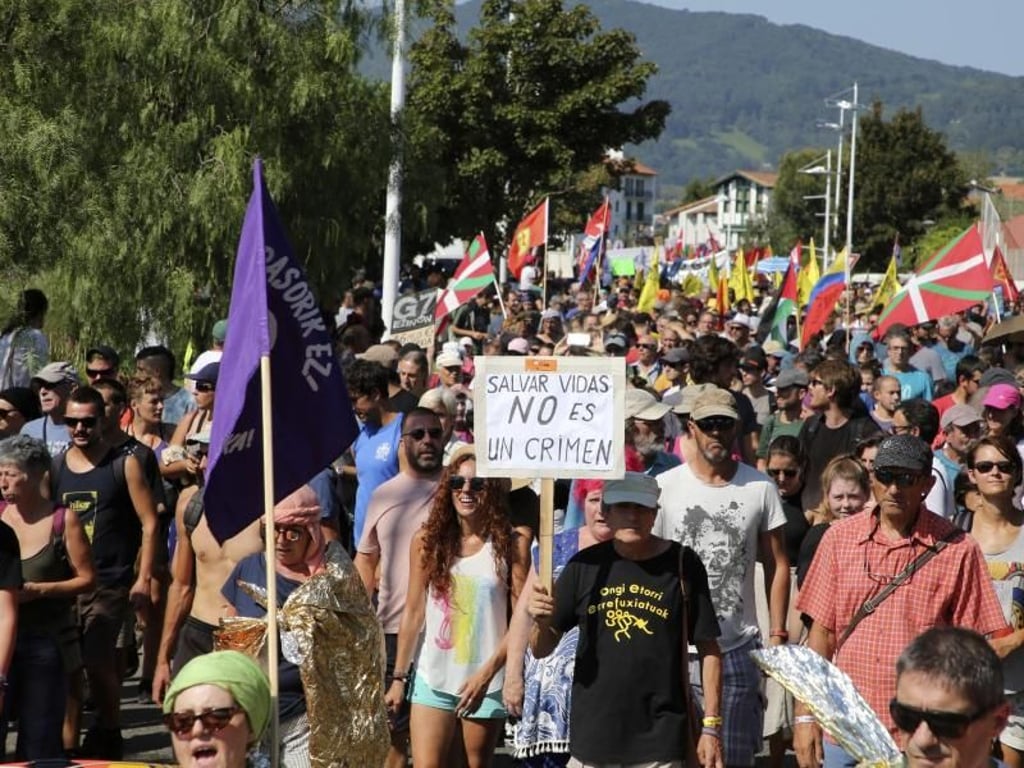 Demonstranten marschieren mit Flaggen und Plakaten während eines Protests. Foto: Bob Edme/AP