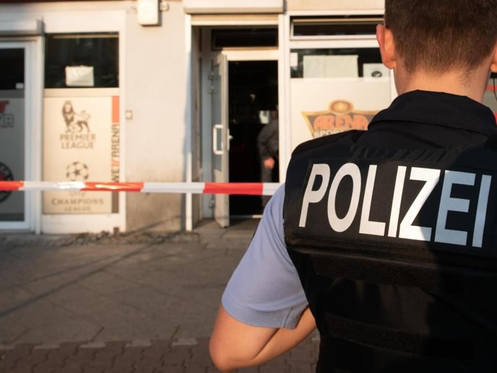 Ein Polizeibeamter steht vor einer Bar am Britzer Damm in Berlin. Dort wurde aus einem Auto heraus auf zwei Menschen geschossen. Foto: Paul Zinken