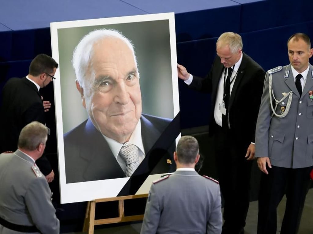Saaldiener stellen vor dem europäischen Trauerakt für Helmut Kohl im EU-Parlament in Straßburg ein Porträt des Altkanzlers auf. Foto: Michael Kappeler