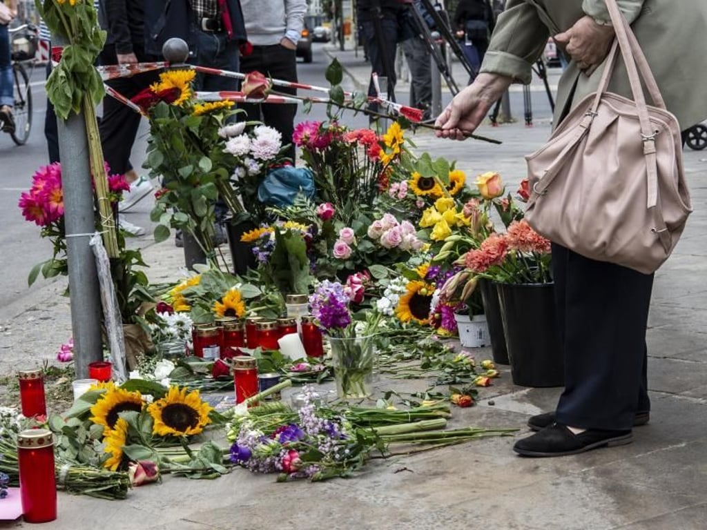 Eine Frau legt Blumen an der Stelle ab, an der vier Menschen bei einem Verkehrsunfall ihr Leben verloren hatten. Foto: Paul Zinken