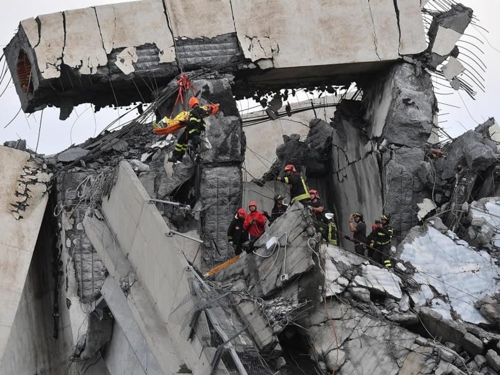 Feuerwehrleute bergen einen Verletzten aus den Trümmern der teilweise eingestürzten Autobahnbrücke Ponte Morandi. Foto: Luca Zennaro/ANSA/AP