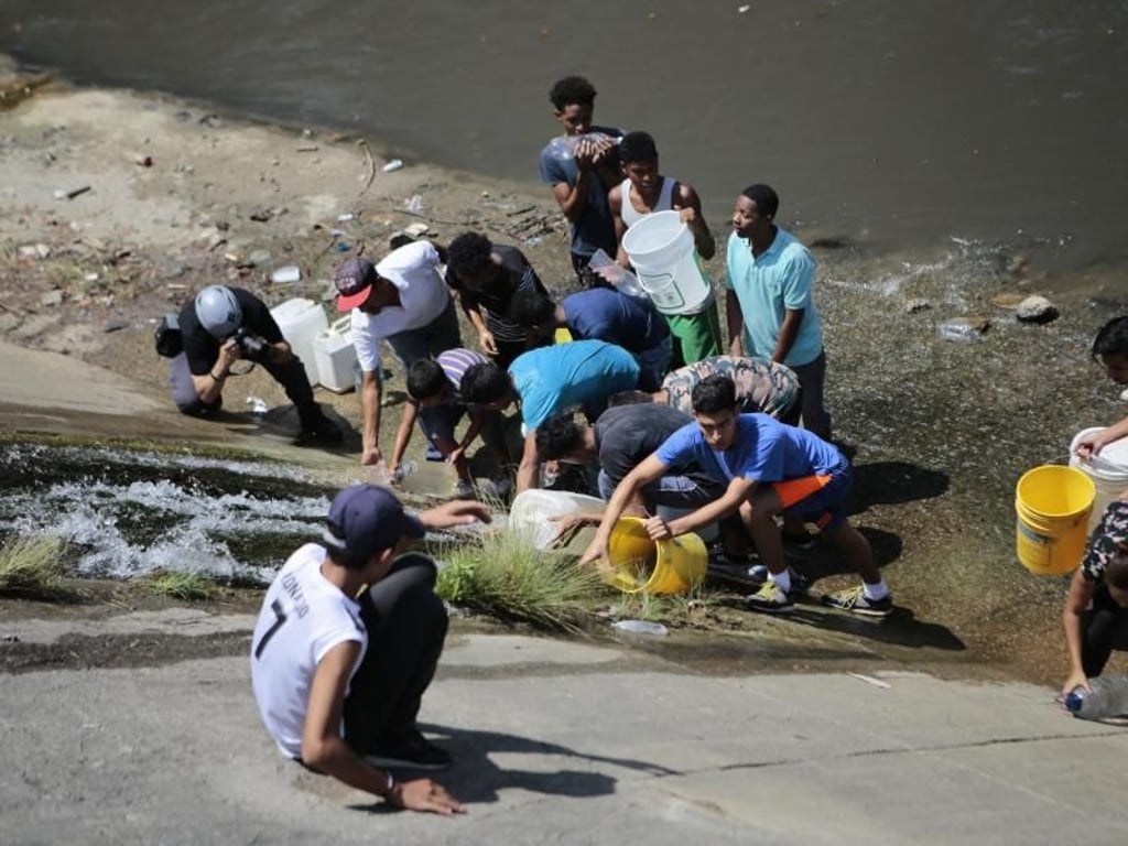 Jeder Tropfen ist kostbar: Menschen versuchen, Eimer und Kanister mit Wasser zu füllen, das an einer Wand entlang fließt. Foto: Rafael Hernandez