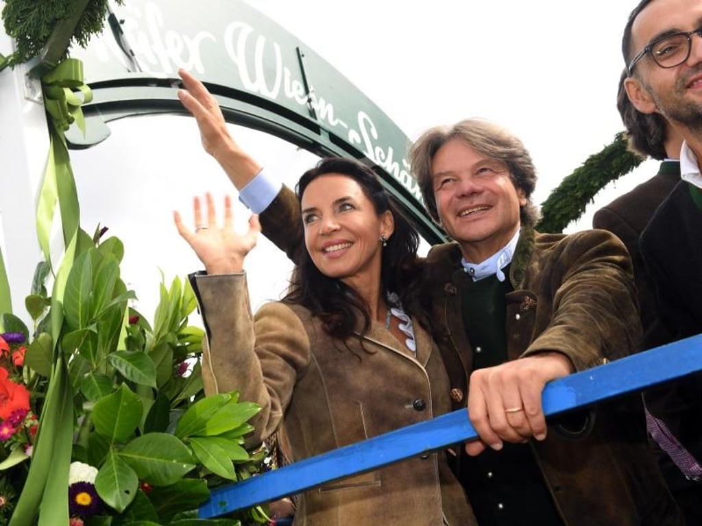 Michael Käfer (M), Wiesnwirt, und seine Frau Clarissa (l) fahren auf dem Oktoberfest beim Einzug der Wiesnwirte auf einem Wagen zum Käferzelt. Foto: Felix Hörhager