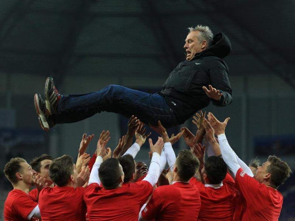 Freiburgs Spieler lassen Trainer Christian Streich nach geschafften Aufstieg durch das 2:1 gegen Paderborn hochleben. Foto: Ina Fassbender