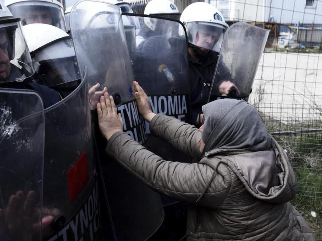 Eine Frau und Polizisten der Bereitschaftspolizei stoßen vor einem Flüchtlingslager westlich von Thessaloniki aufeinander. Foto: Giannis Papanikos/AP