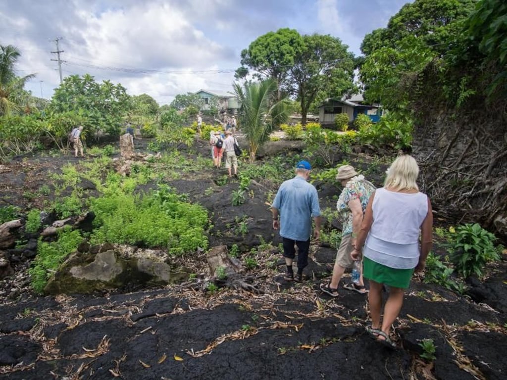 Touristen laufen über erkaltete Lava, zwischen der schon wieder Pflanzen sprießen. Der Ausbruch liegt mehr als ein Jahrhundert zurück. Foto: Philipp Laage