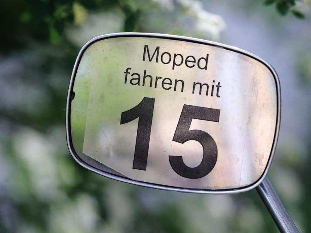 Schriftzug «Moped fahren mit 15» an dem Spiegel eines Mopeds. Foto: Jens Wolf/Archiv