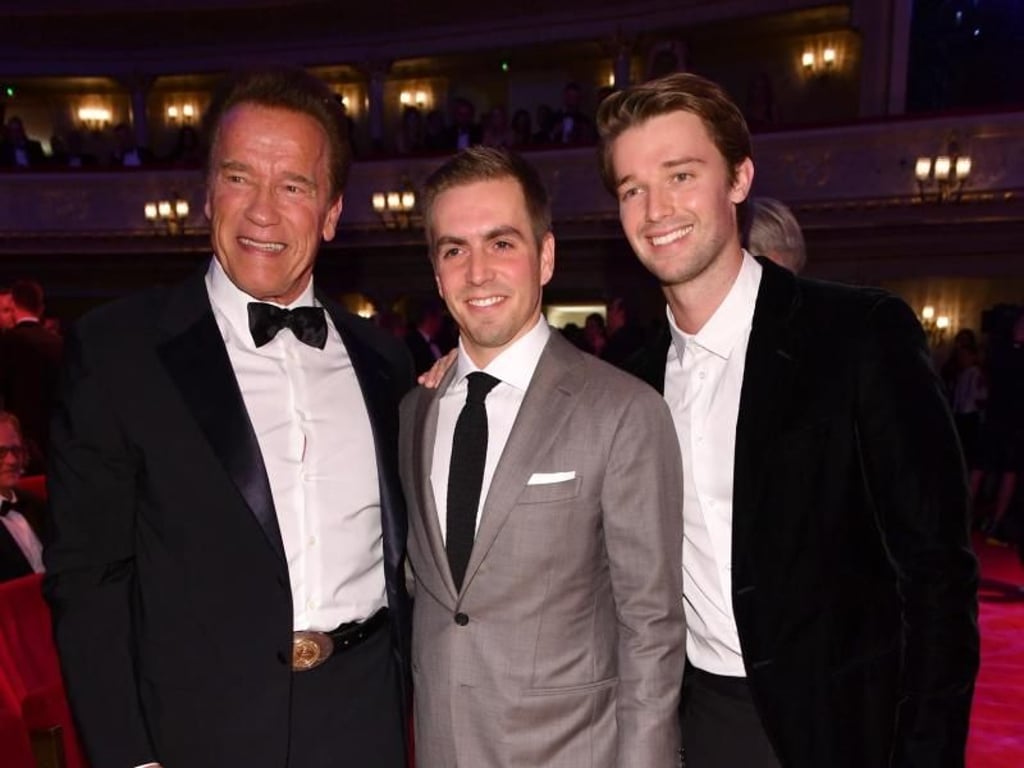 Arnold Schwarzenegger und sein Sohn Patrick haben Philipp Lahm, der als «Sports Icon» geehrt wurde, in ihre Mitte genommen. Foto: Jens Kalaene