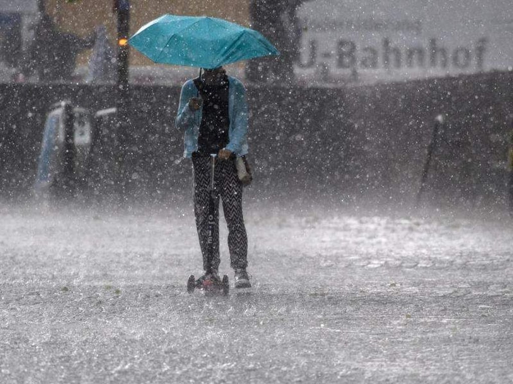 Ein Mädchen mit einem Tretroller fährt in München durch einen Hagelschauer. Foto: Matthias Balk