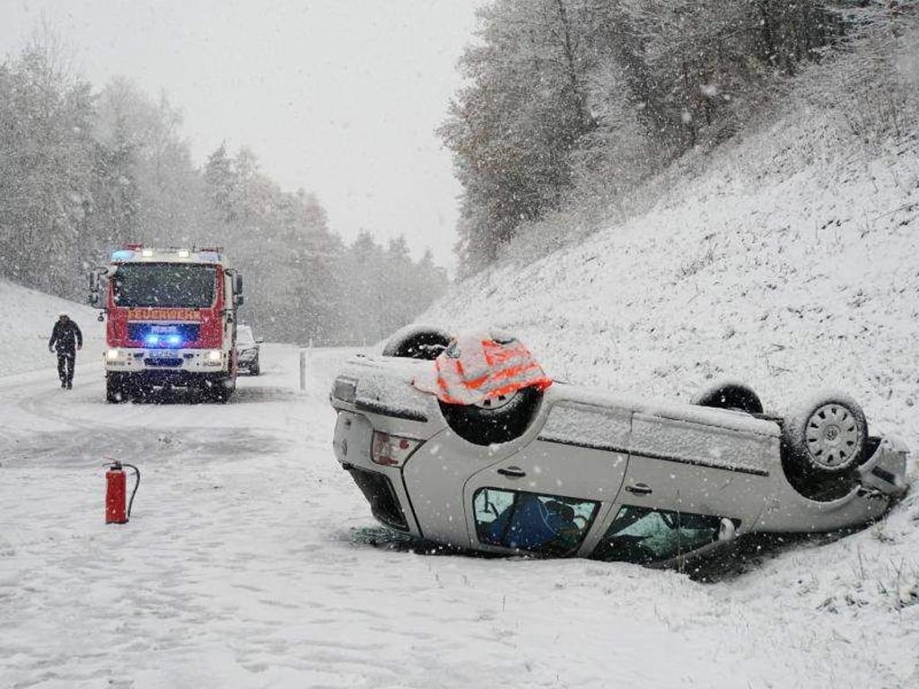 Ein Auto liegt nach einem Unfall auf schneebedeckter Fahrbahn auf der Bundesstraße 14 bei Hahnbach in der Oberpfalz auf dem Dach. Foto: Jürgen Masching