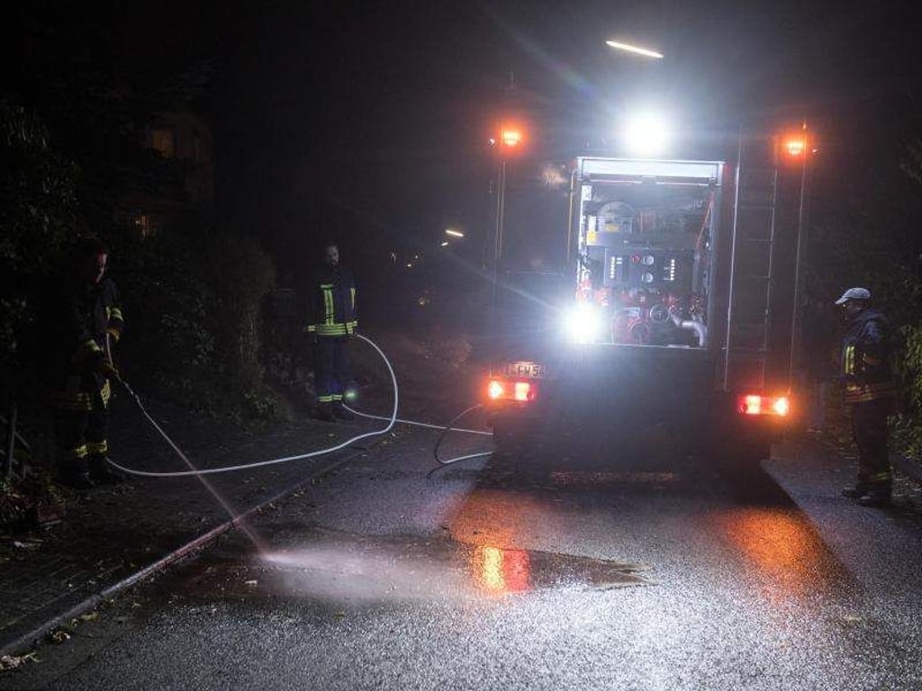 Familientragödie in Wilnsdorf: Feuerwehrmänner reinigen die Straße in der Nähe des Tatorts. Foto: Bernd Thissen