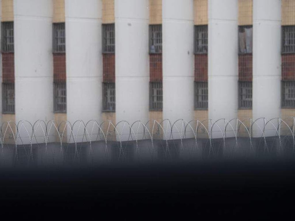 Stacheldraht liegt auf einer Gefängnismauer, im Hintergrund sind Zellenfenster der JVA Stuttgart-Stammheim zu sehen. Foto: Marijan Murat