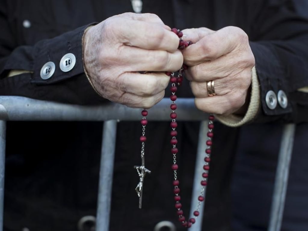Eine Frau betet mit einem Rosenkranz in den Händen, während sie auf die Ankunft von Papst Franziskus wartet. Foto: Mindaugas Kulbis/AP