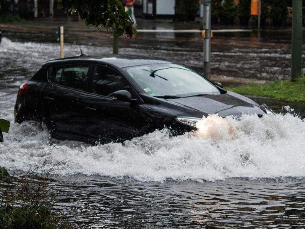Ein Auto fährt in Berlin nach einem starken Gewitter durch eine überflutete Straße. Forschern zufolge sind sintflutartige Regenfälle im Sommer in Zukunft häufiger möglich. Foto: Paul Zinken