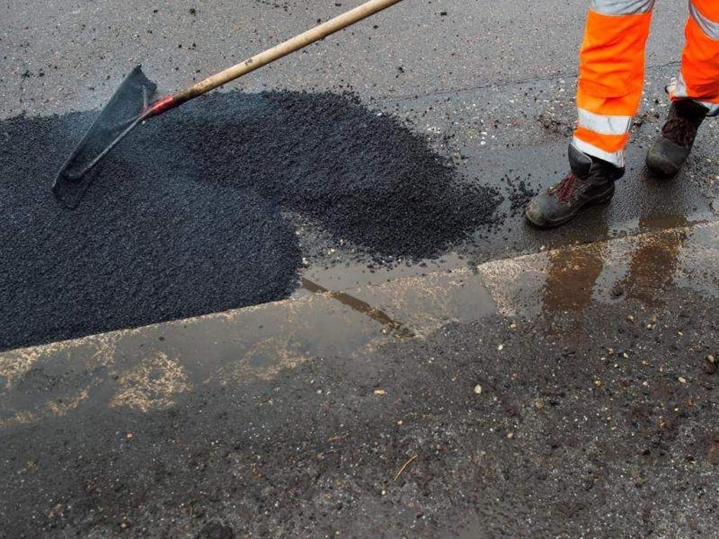 Ein Arbeiter beseitigt Schlaglöcher auf einer Straße. Foto: Arno Burgi/Archivbild