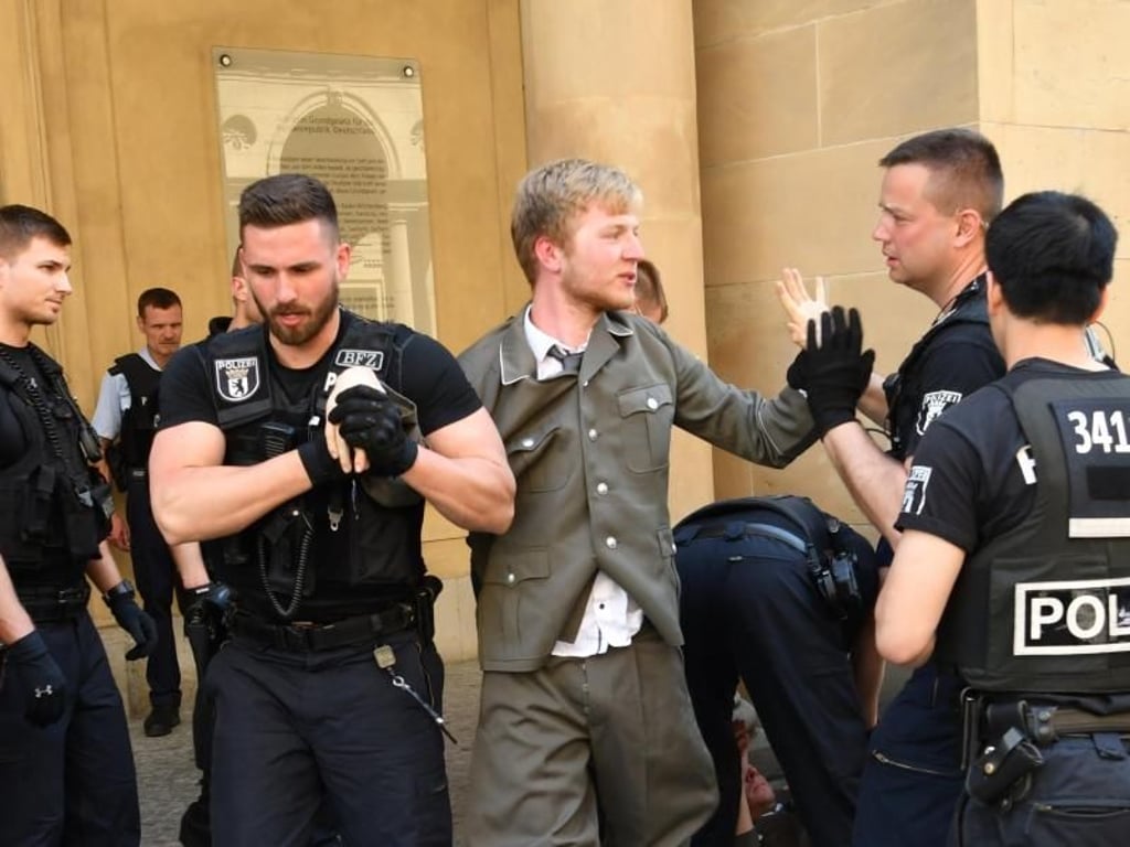 Polizisten führen vor dem Bundesjustizministerium einen Demonstranten der Identitären Bewegung ab. Foto: Paul Zinken