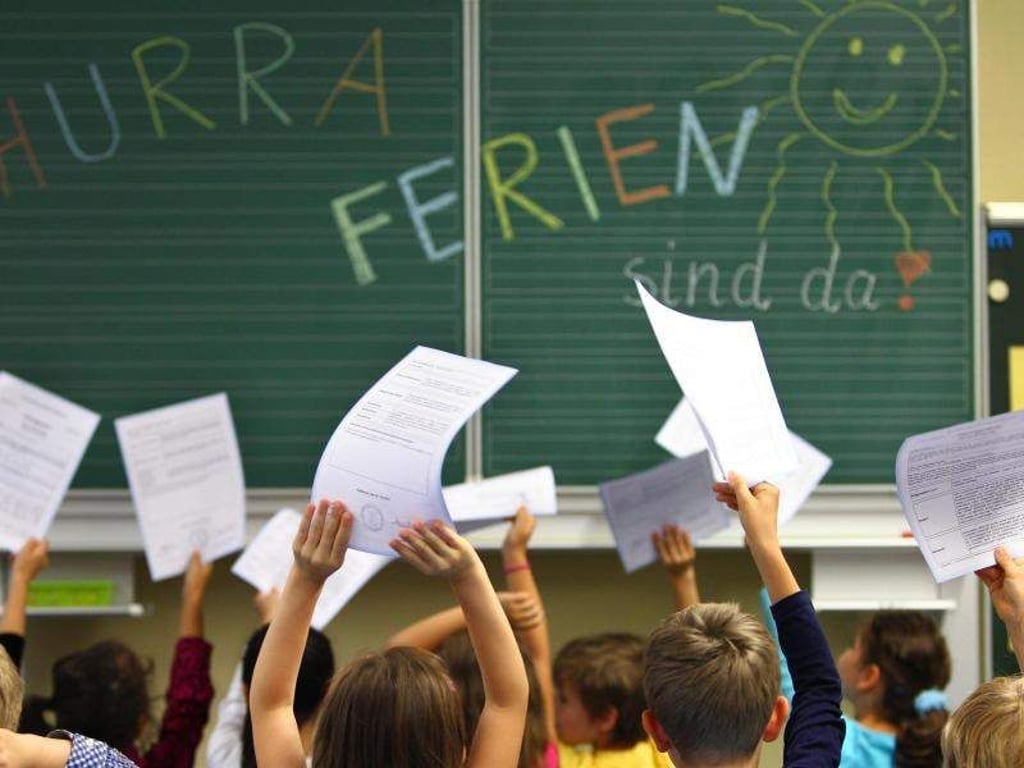 Schüler einer ersten Klasse halten in einer Grundschule ihre Zeugnisse vor einer Tafel hoch. Foto: Karl-Josef Hildenbrand/Archiv