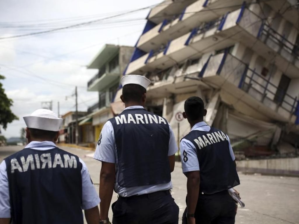 Mitglieder der mexikanischen Marine gehen in Matias Romero an einem teilweise zusammengestürzten Hotel vorbei. Foto: Felix Marquez
