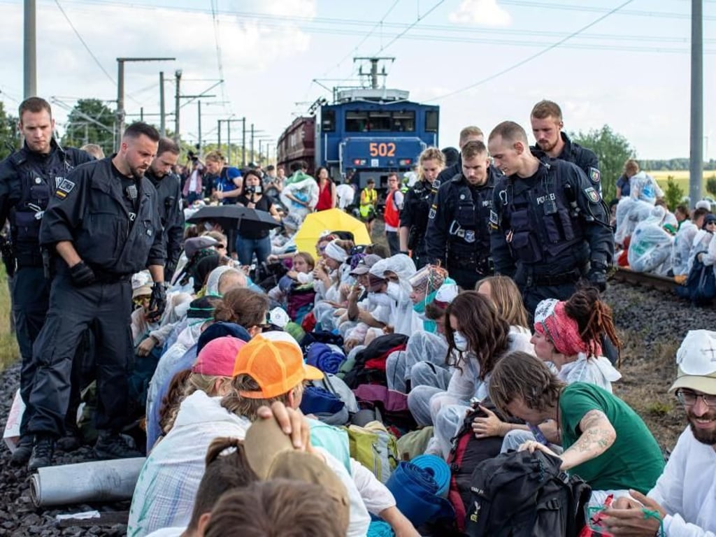 Unter Polizeibeobachtung aus nächster Nähe: Aktivisten blockieren am Freitag die Gleise der Kohle-Transportbahn. Foto: Christoph Reichwein