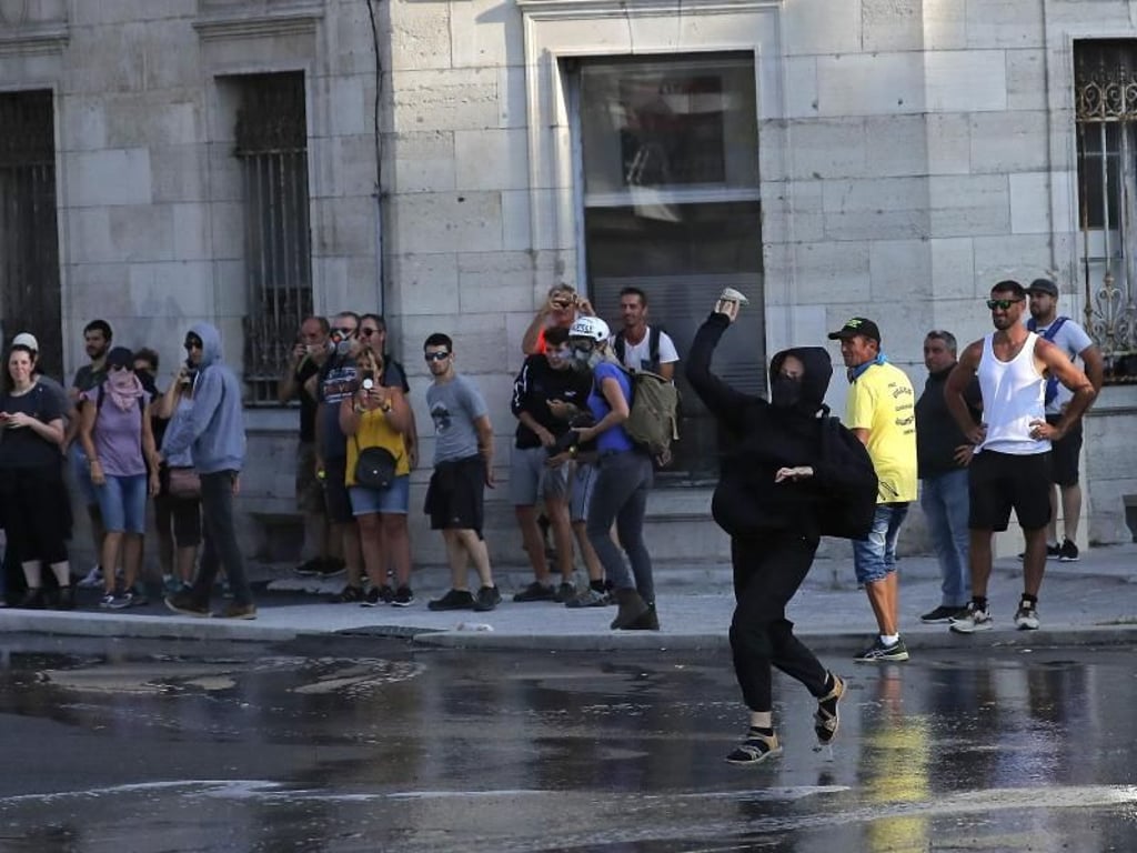 Eine Demonstrantin wirft in Bayonne einen Stein in Richtung Polizei. Foto: Emilio Morenatti/AP