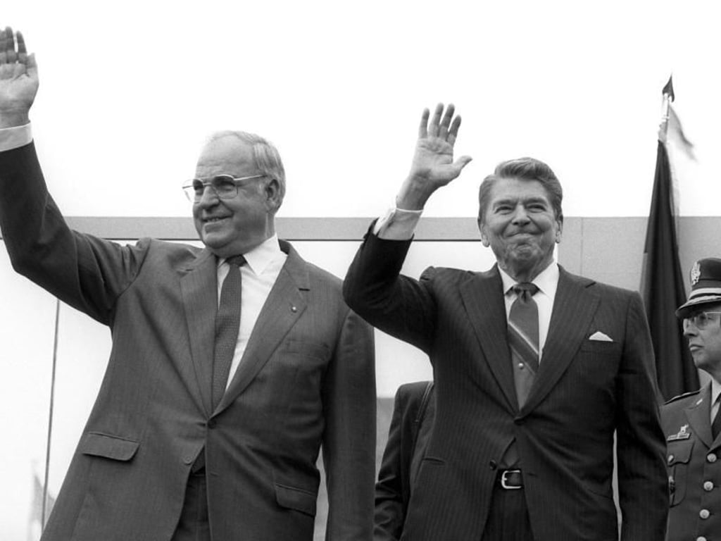 12.06.1987: Bundeskanzler Helmut Kohl und US-Präsident Ronald Reagan winken in West-Berlin an der Mauer zum Brandenburger Tor den Schaulustigen zu. Foto: Roland Holschneider