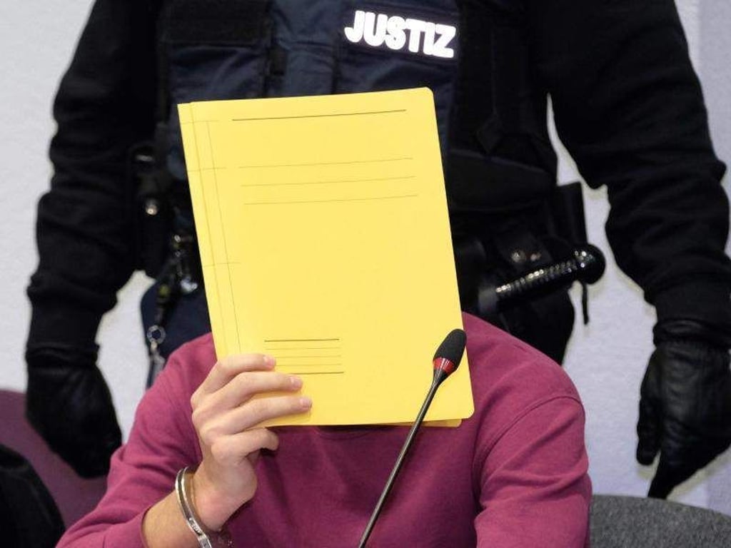 Einer der Angeklagte (M) sitzt im Dessauer Landgericht an der Anklagebank. Foto: Sebastian Willnow/Archivbild