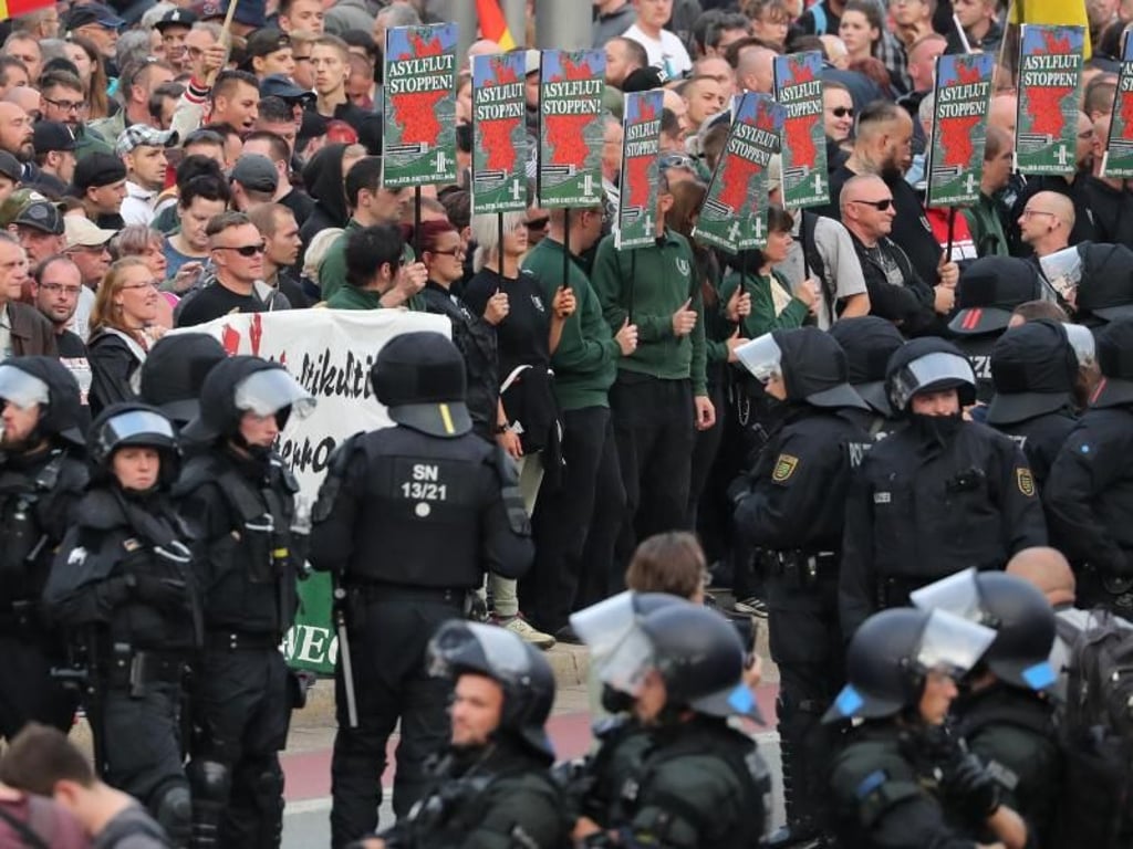 Rechte Demonstranten stehen vor dem Karl-Marx-Monument in Chemnitz. Foto: Jan Woitas