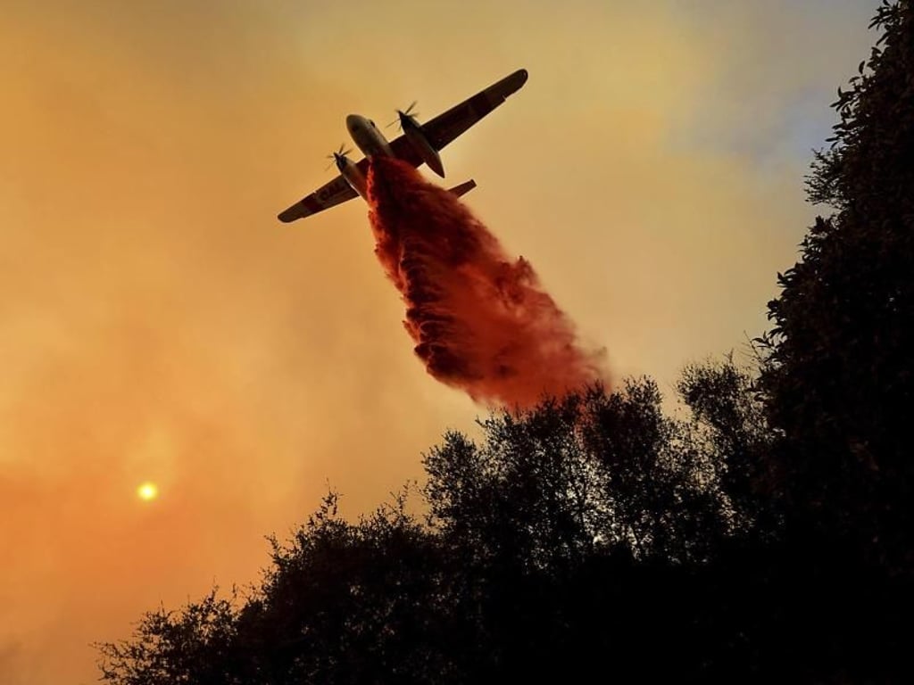 Ein Löschflugzeug lässt in Geyserville Löschmittel über einem Waldbrand ab. Foto: Kent Porter/The Press Democrat
