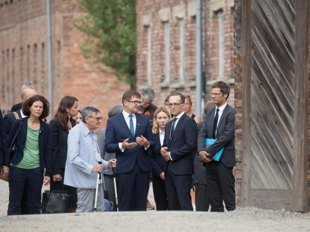 Heiko Maas spricht mit Andrzej Kacorzyk, dem stellvertretenden Direktor der Gedenkstätte Auschwitz-Birkenau, und Marian Turski (mit Krücken), ein ehemaliger Insasse von Auschwitz und Vorsitzender des Jüdischen Historischen Instituts in Warschau. Foto: Michael Kappeler