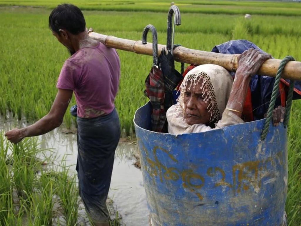 Sie haben nichts mehr: Flüchtlinge der Rohingya tragen eine alte Frau über einen schlammigen Weg, nachdem sie die Grenze zwischen Bangladesch und Myanmar überquert haben. Foto: Md. Mehedi Hasan/Pacific Press via ZUMA Wire