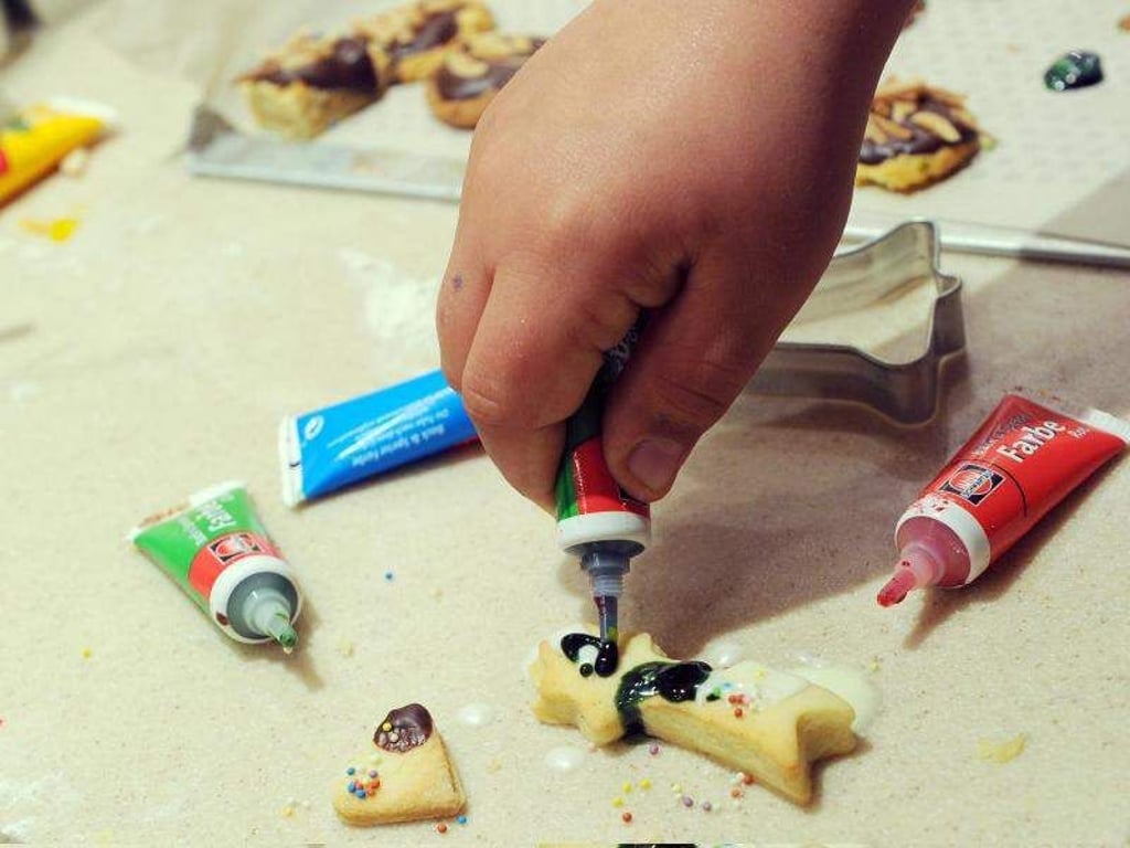 Eine Kind dekoriert beim Backen Kekse. Foto: Jens Kalaene/Illustration