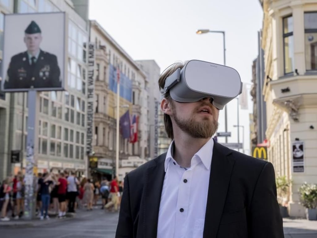 Jonas Rothe, Gru?nder und Gescha?ftsfu?hrer von TimeRide, mit einer Virtual-Reality-Brille am Checkpoint Charlie. Foto: Christoph Soeder