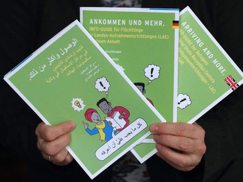 Hände halten Wegweiser für Flüchtlinge und Asylbewerber. Foto: Jens Wolf/Archiv