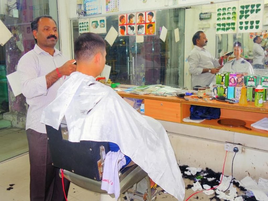 Multikulti beim Friseur: Hier schneidet Mister Saravanan einem chinesischstämmigen Gast die Haare. Foto: Andreas Drouve