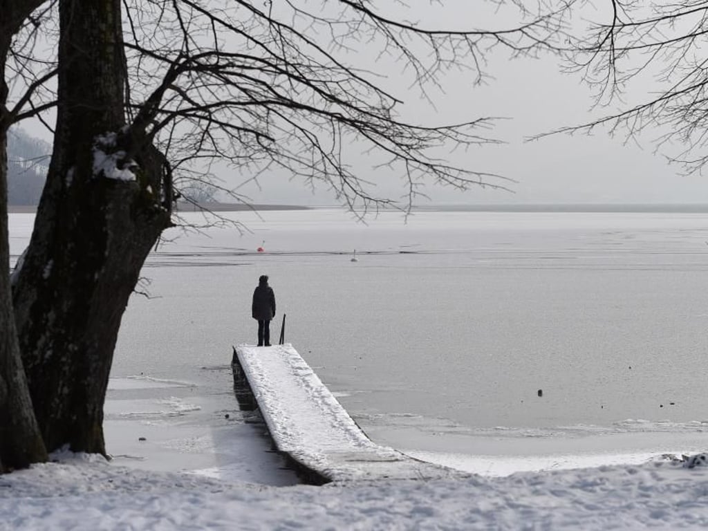 Eine Frau blickt auf den zugefrorenen Tegernsee. In den kommenden Tagen sollen die Temperaturen wieder etwas steigen. Foto: Andreas Gebert