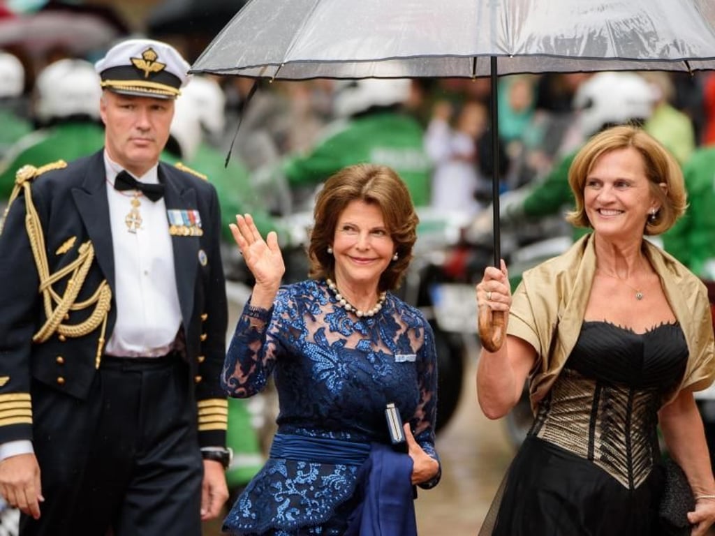 Die schwedische Königin Silvia (m.) und Karin Seehofer (r.) gut beschirmt in Bayreuth. Foto: Nicolas Armer