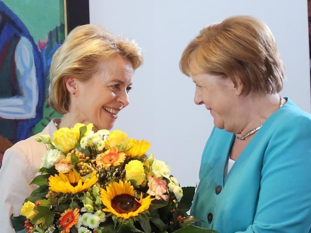 In Berlin überreicht Kanzlerin Merkel der scheidenden Verteidigungsministerin von der Leyen an ihrem letzten Kabinettstag einen Blumenstrauß. Foto: Wolfgang Kumm