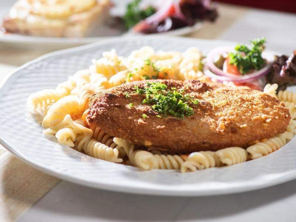 Das Jägerschnitzel ist eine panierte Jagdwurstscheibe, meist serviert mit Spirelli und einer Tomatensauce. Foto: Franziska Gabbert